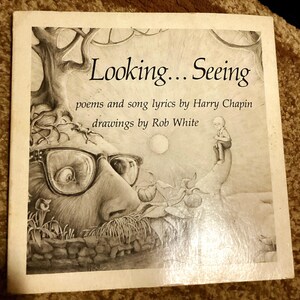 May include: A black and white illustration of a book cover with the title "Looking...Seeing" and the text "poems and song lyrics by Harry Chapin, drawings by Rob White". The cover features a large, whimsical creature with glasses and a small boy standing on a branch.