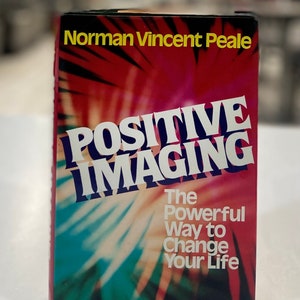 Op de afbeelding: Een boek getiteld "POSITIVE IMAGING" van Norman Vincent Peale. De omslag heeft een rood en blauwgroen burst-ontwerp met witte tekst. De ondertitel luidt "The Powerful Way to Change Your Life."