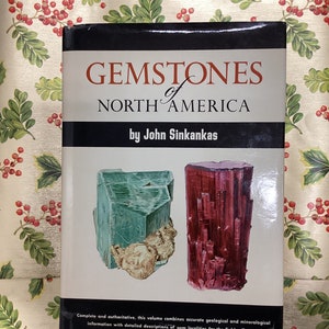 May include: A book titled "Gemstones of North America" by John Sinkankas. The cover features a green and a red gemstone.
