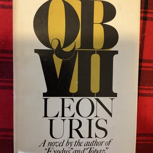 May include: A book cover with the title "OB VII" in large, bold, black and gold letters. The author's name, "LEON URIS", is printed below the title in black letters. The text "A novel by the author of "Exodus" and "Topaz" is printed below the author's name.