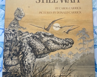 May include: A vintage book cover with the title "The Crocodiles Still Wait" by Carol Carrick, with illustrations by Donald Carrick. The cover features a crocodile in a swamp setting with a dinosaur in the background.
