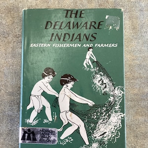 Könnte beinhalten: Ein grüner Buchumschlag mit dem Titel "The Delaware Indians: Eastern Fishermen and Farmers" und einer Illustration von zwei Kindern, die ein Fischernetz ziehen. Das Buch ist Teil der Morrow Eagle Library Edition.