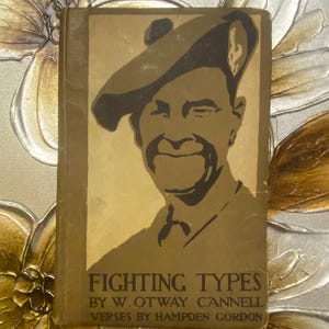 Puede incluir: Un libro antiguo titulado "Fighting Types" con una ilustración en tonos sepia de un hombre con sombrero en la portada. El título del libro y el nombre del autor están impresos en una fuente serif clásica. El fondo presenta adornos florales.