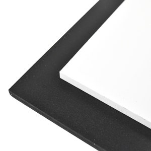 May include: A black foam board with a white foam board on top of it.