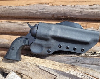 Könnte beinhalten: Eine schwarze Pistole in einem schwarzen Holster mit strukturierter Oberfläche. Das Holster hat sechs schwarze Schrauben an der Seite.