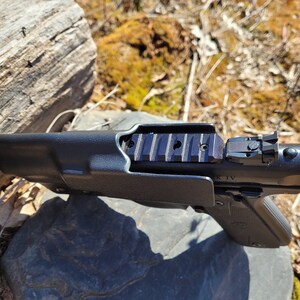 May include: A black handgun with a black holster. The handgun has a black polymer frame and a black metal slide. The slide has a black polymer sight and a black metal rail on top. The holster is made of black polymer and has a black polymer belt loop.