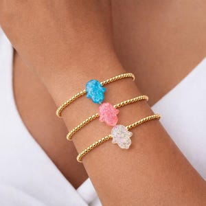 May include: A set of three ceramic mugs with a speckled, cream-colored glaze. Each mug features a different hand-painted floral design in shades of blue, green, and yellow. The mugs have a simple, rounded shape and a comfortable handle.