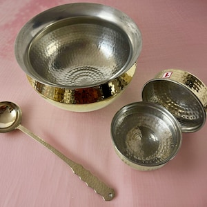 May include: A set of three hammered brass bowls, one large and two smaller, with a matching ladle. The bowls have a shiny, gold finish.