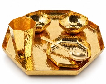 May include: A gold-colored metal set featuring a large octagonal tray, a tall hexagonal tumbler, two small hexagonal bowls, a small hexagonal plate, and a smooth spoon. Each piece displays a consistent hammered, dimpled texture.