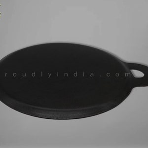 K&ouml;nnte beinhalten: Eine schwarze Gusseisen-Dosa-Pfanne mit einem einzigen Griff. Die Pfanne ist rund und hat einen leicht erh&ouml;hten Rand. Die Pfanne wird in Indien hergestellt.