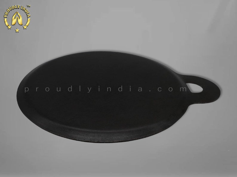 K&ouml;nnte beinhalten: Eine schwarze Gusseisen-Dosa-Pfanne mit einem einzigen Griff. Die Pfanne ist rund und hat einen leicht erh&ouml;hten Rand. Die Pfanne wird in Indien hergestellt.