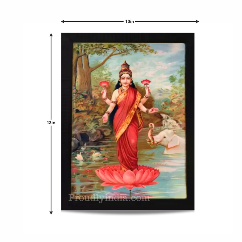May include: A framed painting of a Hindu goddess standing on a pink lotus flower. She is wearing a red sari and holding two pink lotus flowers in her hands. The painting is set against a background of a lush green forest and a blue sky. The frame is black and measures 10 inches by 13 inches.