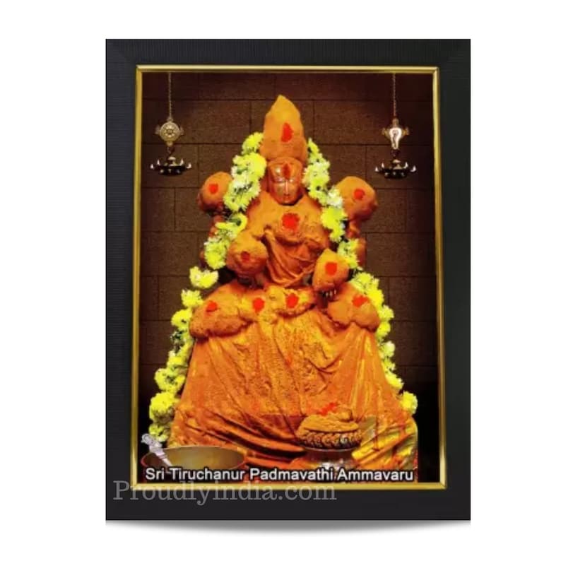 Puede incluir: Una imagen enmarcada de una deidad hind&uacute;, Sri Tiruchanoor Padmavathi Ammavaru, adornada con flores amarillas y polvo de c&uacute;rcuma. La imagen est&aacute; sobre un fondo de pared de ladrillo marr&oacute;n.
