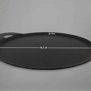 K&ouml;nnte beinhalten: Eine schwarze Gusseisen-Dosa-Pfanne mit einem Griff. Die Pfanne hat einen Durchmesser von 10,2 Zoll und ist 1,5 cm dick.