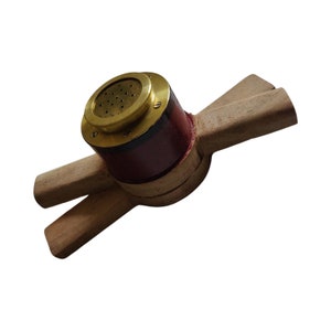 Könnte beinhalten: Ein Werkzeug aus Holz mit einer Messing-Oberseite und einer rot-schwarzen Basis. Das Werkzeug hat zwei Holzarme, die sich von der Basis aus erstrecken.