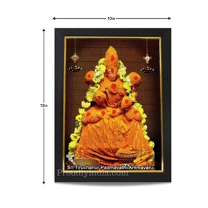 Puede incluir: Una imagen enmarcada de una deidad hind&uacute;, Sri Tiruchanoor Padmavathi Ammavaru, con una t&uacute;nica amarilla y naranja, rodeada de flores. La imagen mide 25,4 cm de ancho y 33 cm de alto.