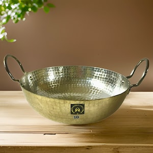 May include: A hammered aluminium serving bowl with two handles. The bowl is silver in colour and has a textured surface. The bowl is labelled "Proudly India" and "10".