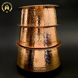 May include: A set of three copper serving bowls with a hammered finish. The bowls are stacked on top of each other, with the largest bowl at the bottom and the smallest bowl at the top.