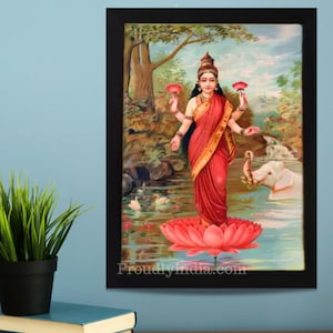 May include: A framed painting of a Hindu goddess standing on a pink lotus flower. She is wearing a red sari and holding two pink lotus flowers in her hands. A white elephant is in the background.