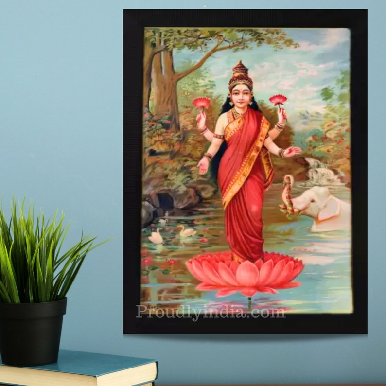 May include: A framed painting of a Hindu goddess standing on a pink lotus flower. She is wearing a red sari and holding two pink lotus flowers in her hands. A white elephant is in the background.