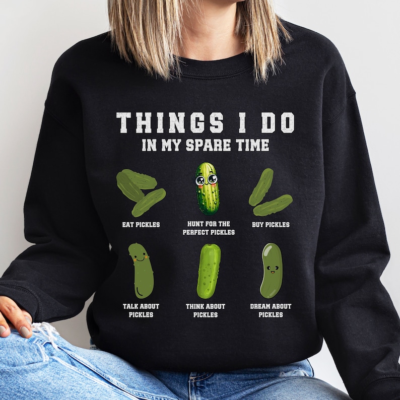 May include: Black sweatshirt with a white graphic of a list of things the wearer does in their spare time, all related to pickles. The graphic includes the text "Things I do in my spare time" and illustrations of pickles with faces.