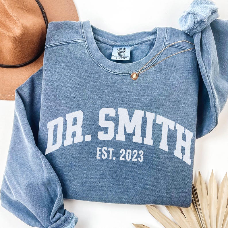 May include: A blue sweatshirt with the text "DR. SMITH EST. 2023" in white.