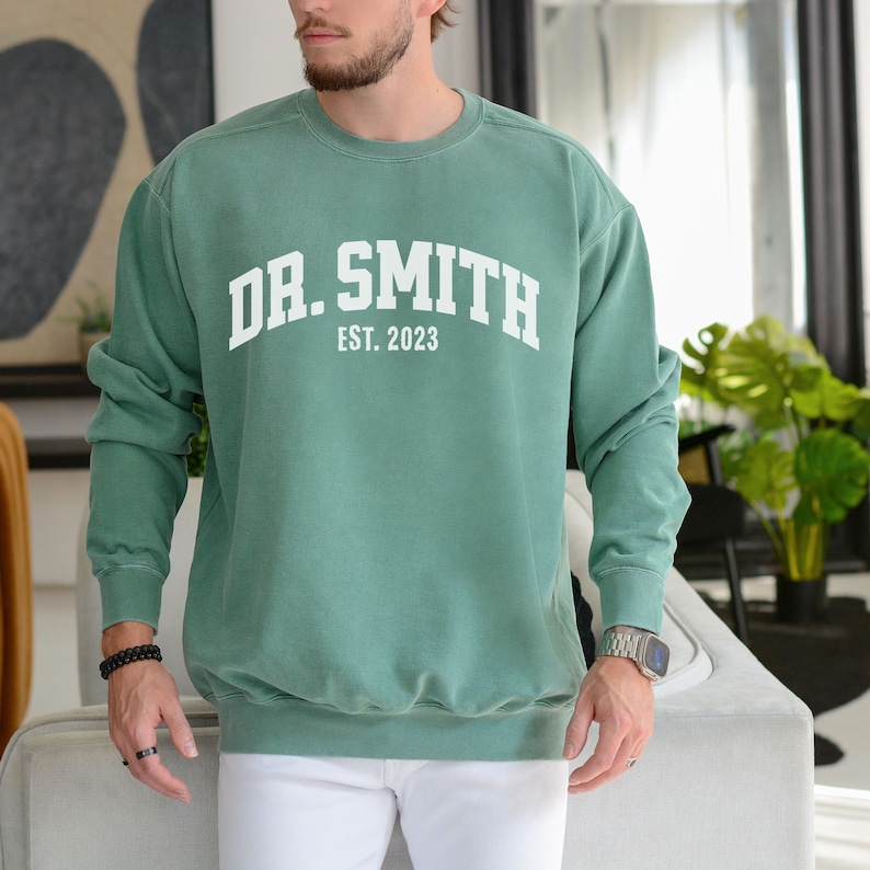 May include: A green sweatshirt with the text "DR. SMITH EST. 2023" in white.