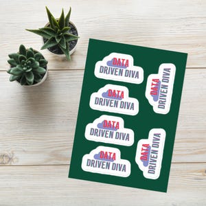 Könnte beinhalten: Ein Bogen mit Aufklebern mit dem Text "DATA DRIVEN DIVA" in Rot und Blau. Die Aufkleber sind weiß mit einem wolkenförmigen Design. Zwei kleine Sukkulenten in Töpfen befinden sich auf einer Holzoberfläche.