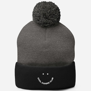 May include: Gray and black beanie with a pom pom on top. The beanie has a black cuff with a white smiley face and the text "COOL CODERS CLUB".
