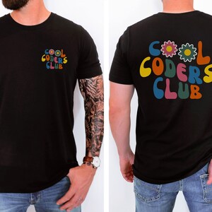 May include: Black t-shirt with a retro-style graphic on the front and back that says "Cool Coders Club" in colourful letters with flowers.