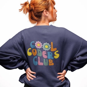 Peut inclure: Un sweat-shirt bleu marine avec un motif color&eacute; au dos qui dit "COOL CODERS CLUB" avec des fleurs autour du texte.