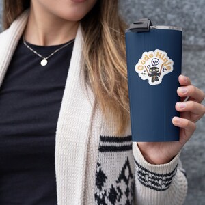 May include: A navy blue travel mug with a white sticker featuring a cartoon ninja holding two swords and the text "Code Ninja".