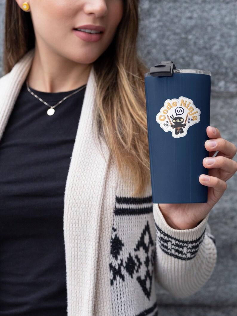 May include: A navy blue travel mug with a white sticker featuring a cartoon ninja holding two swords and the text "Code Ninja".