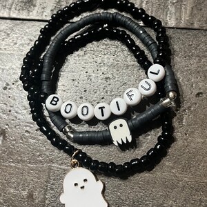Könnte beinhalten: Drei schwarze Perlenarmbänder mit einem weißen Geisteranhänger und einem weißen Anhänger mit dem Wort "BOOTIFUL".