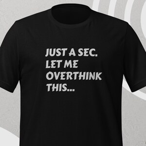 Front view, black color, flat mock-up, Funny Quote T-Shirt - Printed With: 'Just a Sec, Let Me Overthink This' - Unisex Tee for Fans of Funny, Relatable Humor