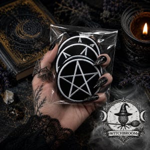 May include: A set of circular embroidered patches featuring a white pentagram design on a black background, enclosed in a clear plastic bag. The patches have a stitched border and are held together in a stack, displaying a consistent graphic style.