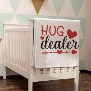 May include: White baby blanket with red hearts and the text "HUG dealer" in black lettering.