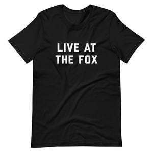 Puede incluir: Camiseta negra de manga corta con texto blanco que dice "LIVE AT THE FOX".