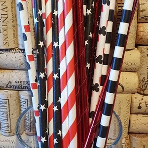 May include: A close-up of a variety of red and black striped paper straws with white stars, red and white striped paper straws, and red and white striped paper straws with black clubs. The straws are in a clear glass jar. The text "Casino Night Mix" is visible at the bottom of the image.