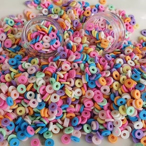 May include: A large pile of colorful donut-shaped sprinkles. The sprinkles are in various shades of pink, blue, green, yellow, and white.