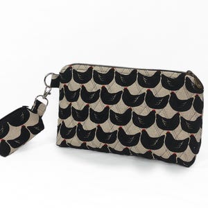 cosmetic bag with black chickens quilted on cotton canvas. A small extra zipper pouch hooked on the side.