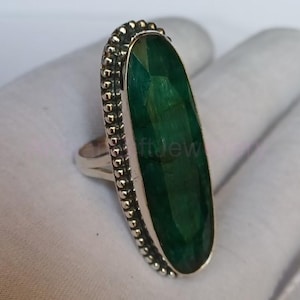 Puede incluir: Un anillo de plata con una gran piedra preciosa verde de forma ovalada engastada en un engaste de cuentas.