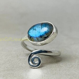 May include: A silver ring with a blue labradorite gemstone set in a swirl design.