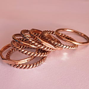 K&ouml;nnte beinhalten: Ein Satz von sechs Kupferringen, einige mit einem gedrehten Seil-Design und andere mit einer glatten Oberfl&auml;che. Die Ringe sind &uuml;bereinander gestapelt.