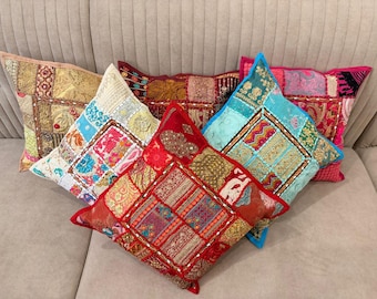 May include: Five square throw pillows featuring a patchwork design of various fabrics, intricate embroidery, metallic thread accents, and small mirror embellishments. The pillows display a vibrant color palette including red, gold, blue, and pink.