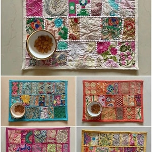 Könnte beinhalten: Vier farbenfrohe Patchwork-Platzsets mit Stickereien. Jedes Platzset hat eine andere Farbgebung, darunter Weiß, Blau, Orange und Pink. Auf jedem Platzset befindet sich eine kleine weiße Schale mit Mandeln.