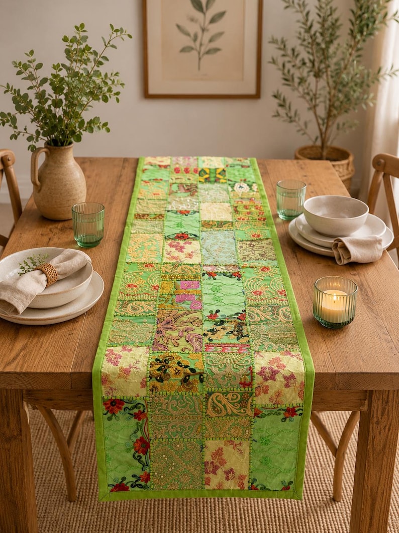 Peut inclure: Un chemin de table rectangulaire compos&eacute; d'un assemblage de carr&eacute;s de tissu verts. Le chemin pr&eacute;sente des broderies complexes, des motifs floraux et des accents de fils m&eacute;talliques dans des tons vert lime, &eacute;meraude et olive avec une bordure unie.