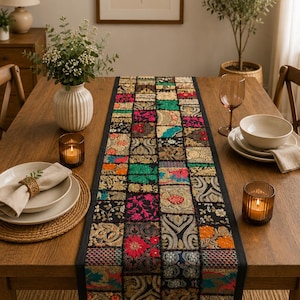 Peut inclure: Un chemin de table rectangulaire compos&eacute; d'un assemblage de carr&eacute;s de tissu. Chaque carr&eacute; pr&eacute;sente des broderies complexes, des d&eacute;tails en fil m&eacute;tallique et des couleurs vives comme le fuchsia, le vert, l'orange et l'or sur fond noir.