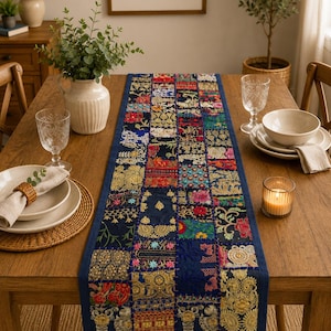 Peut inclure: Un chemin de table rectangulaire pr&eacute;sentant un motif patchwork compos&eacute; de divers carr&eacute;s de tissu bleu fonc&eacute;. Chaque carr&eacute; est orn&eacute; de broderies florales multicolores complexes, de d&eacute;tails en fil m&eacute;tallique dor&eacute; et de petites paillettes vari&eacute;es.