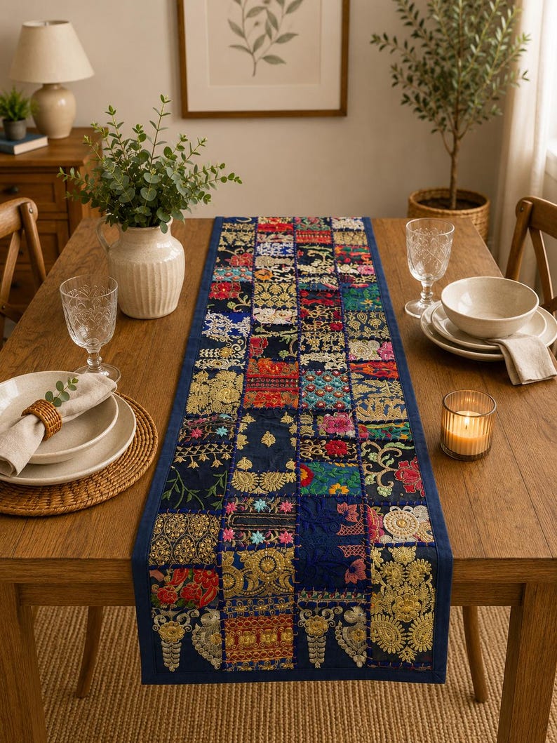 Peut inclure: Un chemin de table rectangulaire pr&eacute;sentant un motif patchwork compos&eacute; de divers carr&eacute;s de tissu bleu fonc&eacute;. Chaque carr&eacute; est orn&eacute; de broderies florales multicolores complexes, de d&eacute;tails en fil m&eacute;tallique dor&eacute; et de petites paillettes vari&eacute;es.